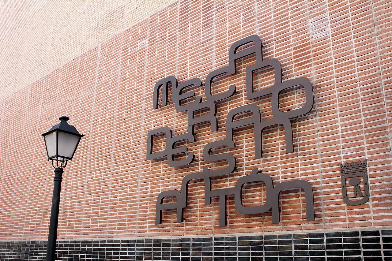 Fachada de ladrillo del Mercado de San Antón con su rótulo metálico y una farola